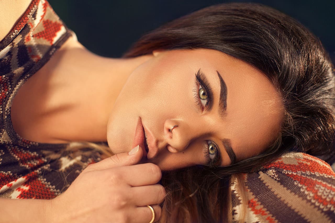 A woman lying on her side, her brows shaped full and defined