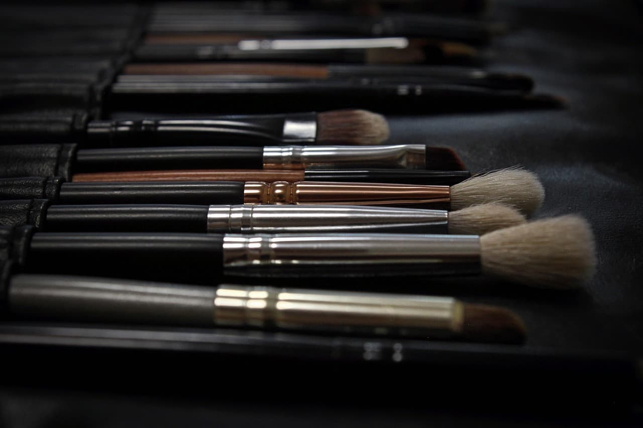 A row of make-up brushes laid out on a dark cloth