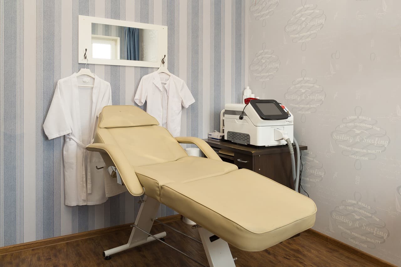 A treatment couch in a clean beauty room with white gowns on the wall